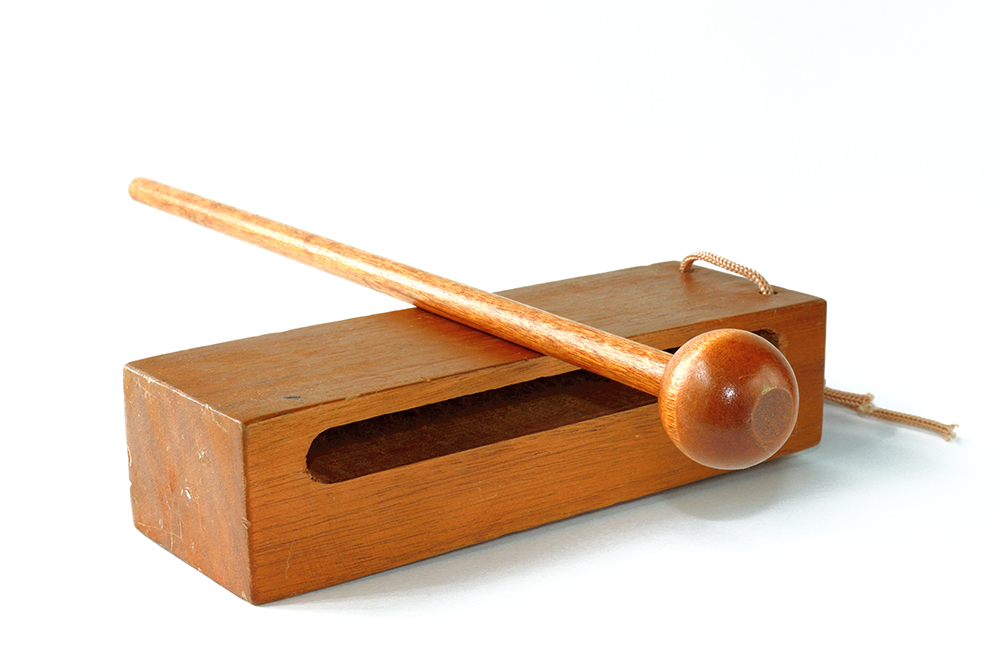 Caja china, instrumento de madera consistente en una caja rectangular con hueco y una baqueta con una bola de madera en la punta